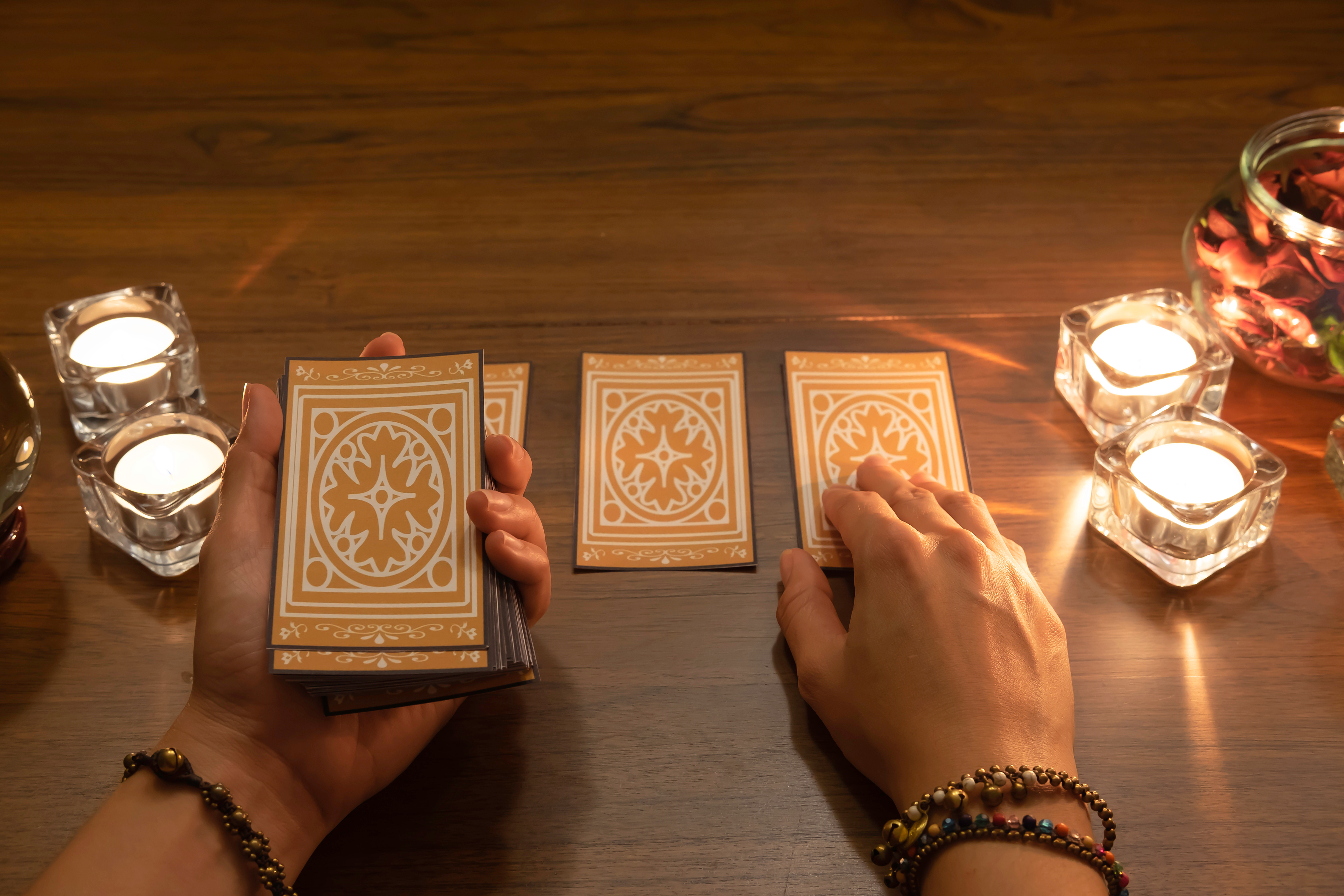 hands pulling tarot card with candle light