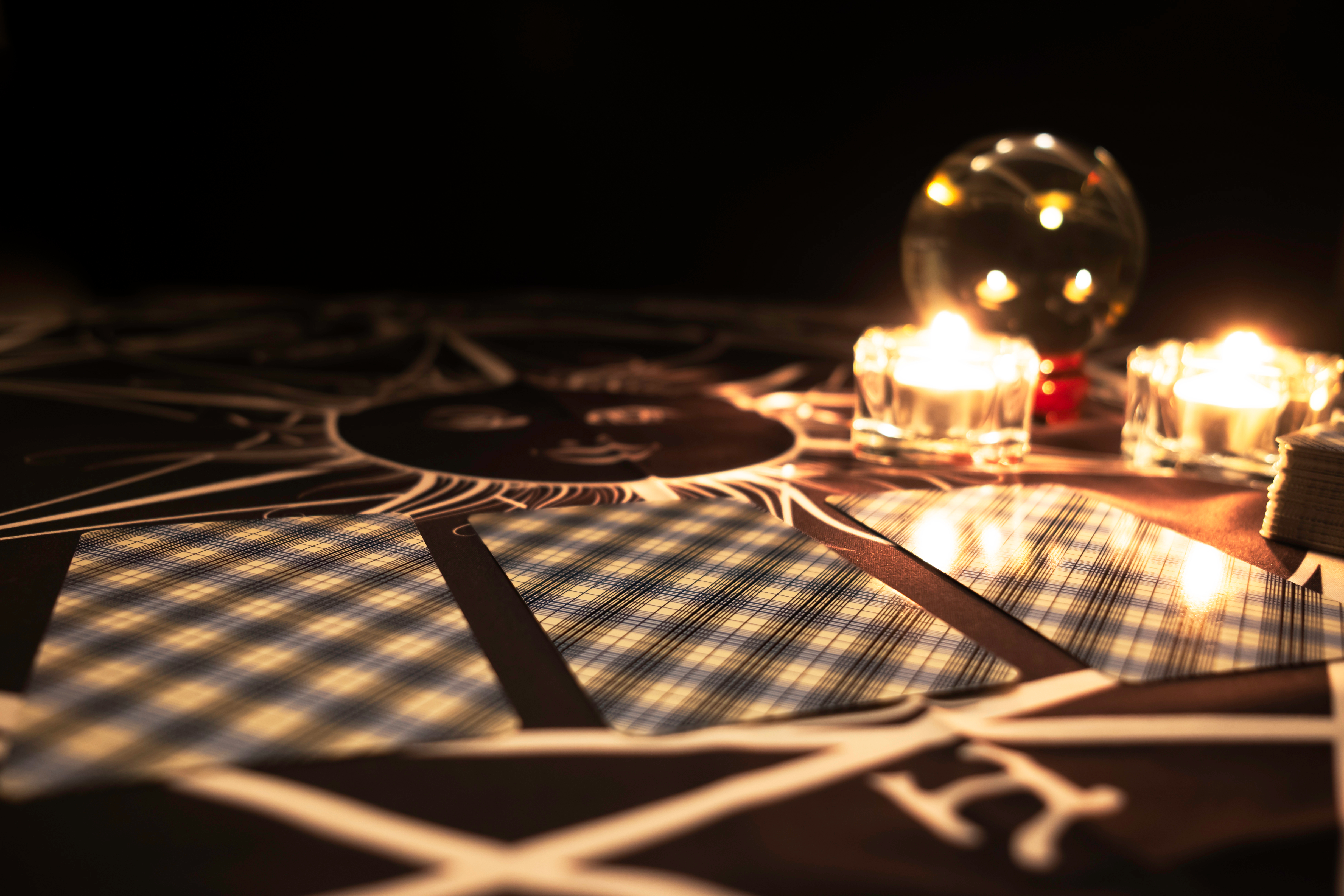 A row of three tarot cards face down near a candle