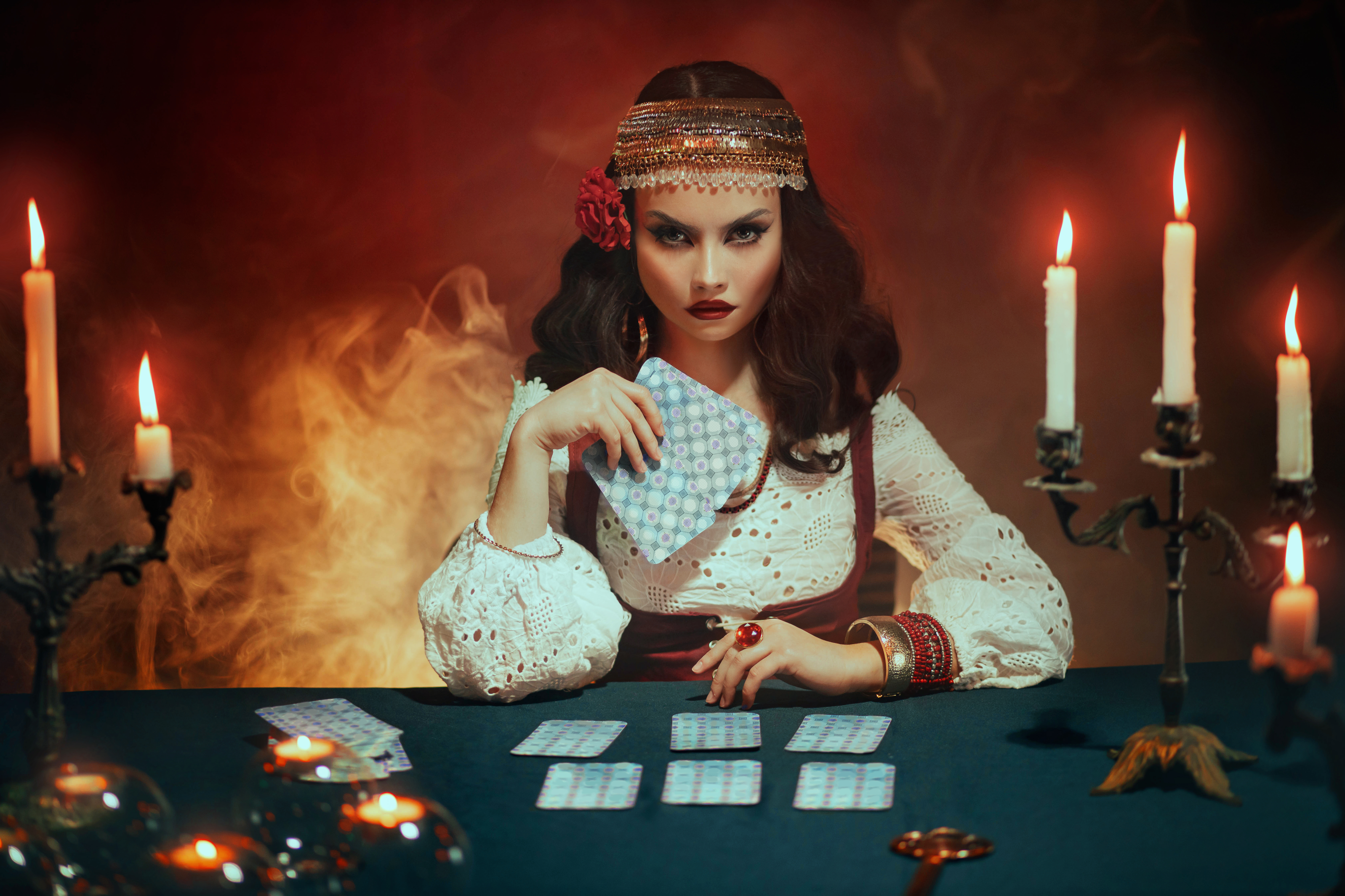 A psychic reader sitting at a table and holding cards.
