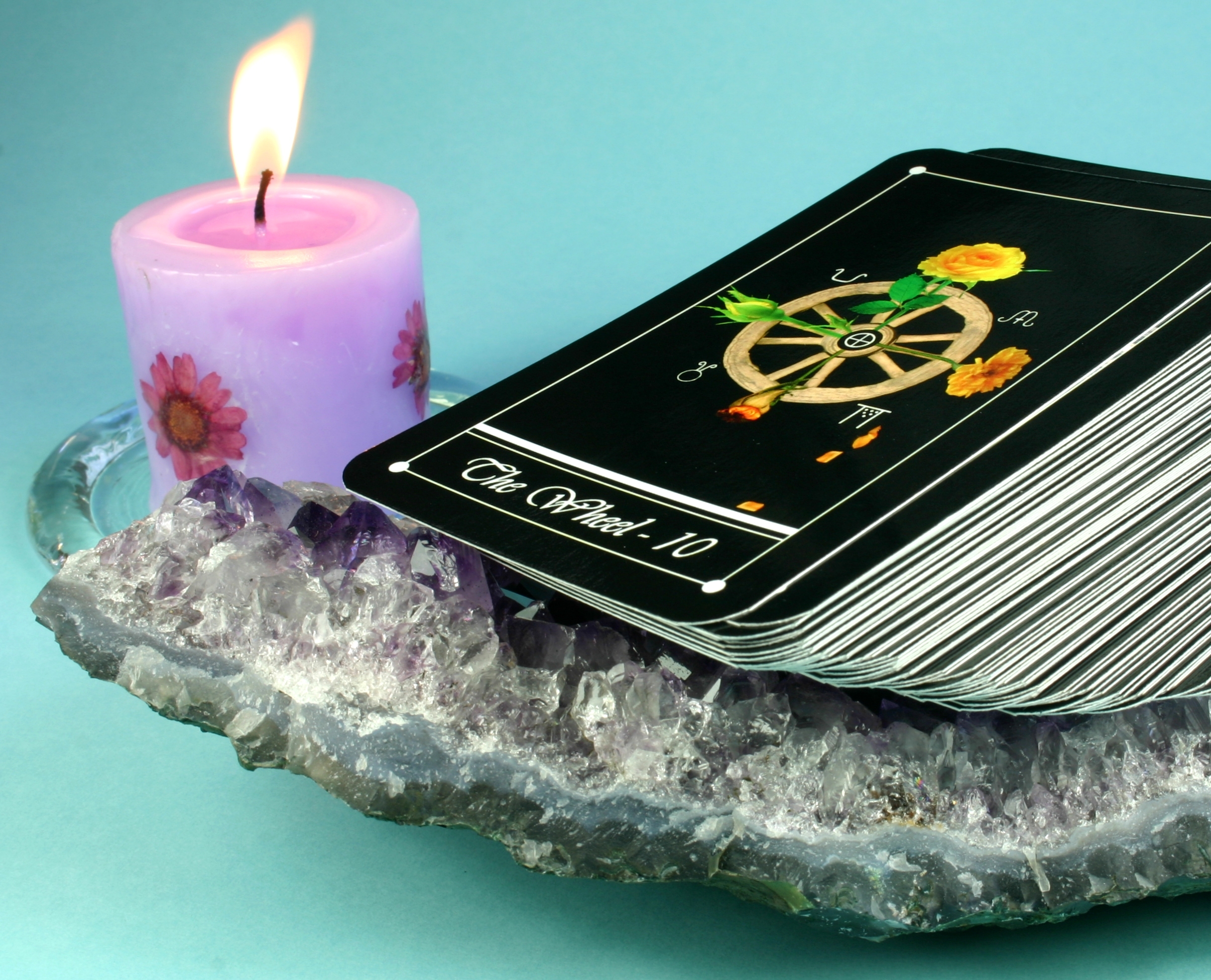 A pack of tarot cards being cleansed using crystals and a candle